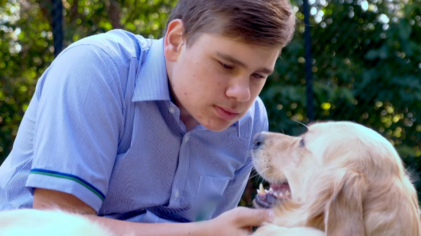 Oliver leans down to pat Seeing Eye Dog Sadie